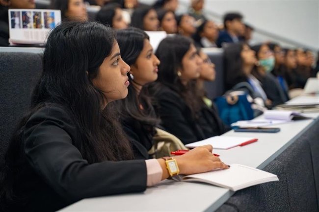 A group of students in a lecture theatre, listening and looking attentive